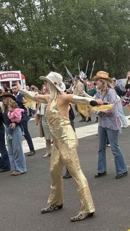 Kirsten Mann in a gold jumpsuit dancing with the crowd