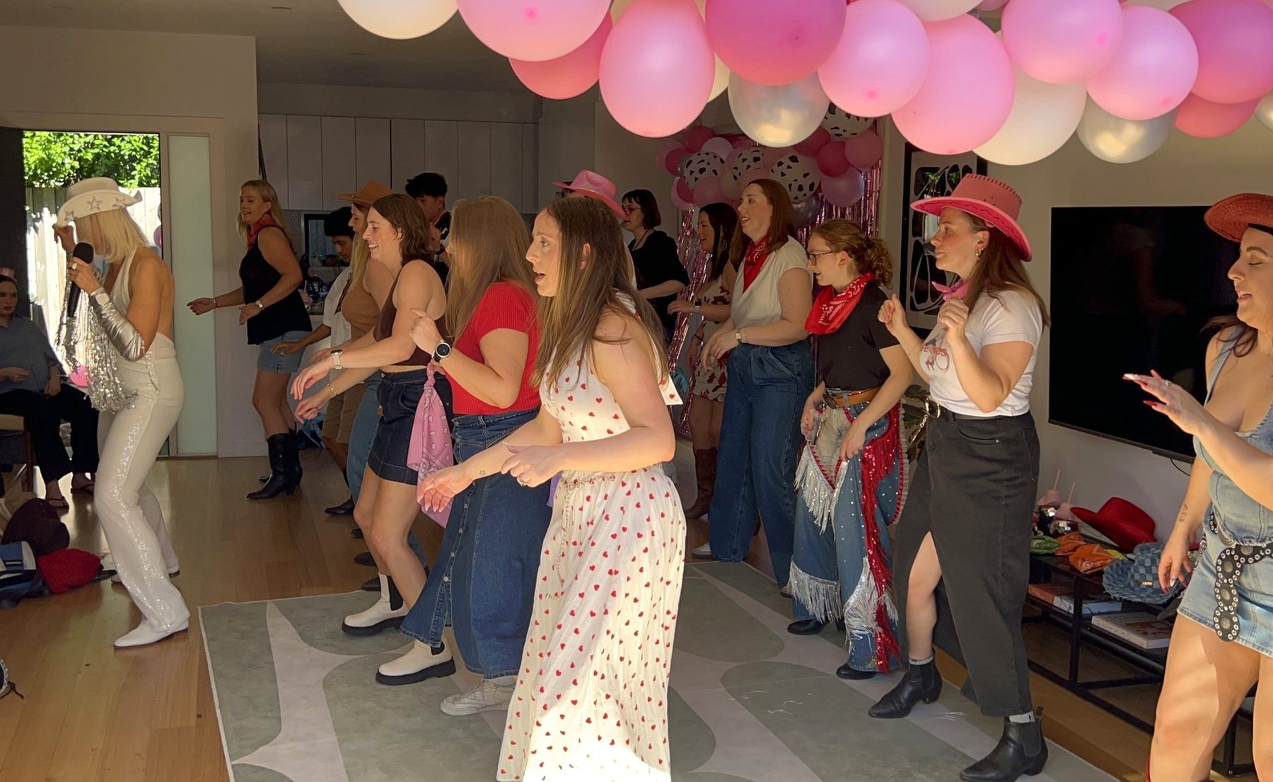 A private Boot Scooting Society party — guests line dancing together under balloons